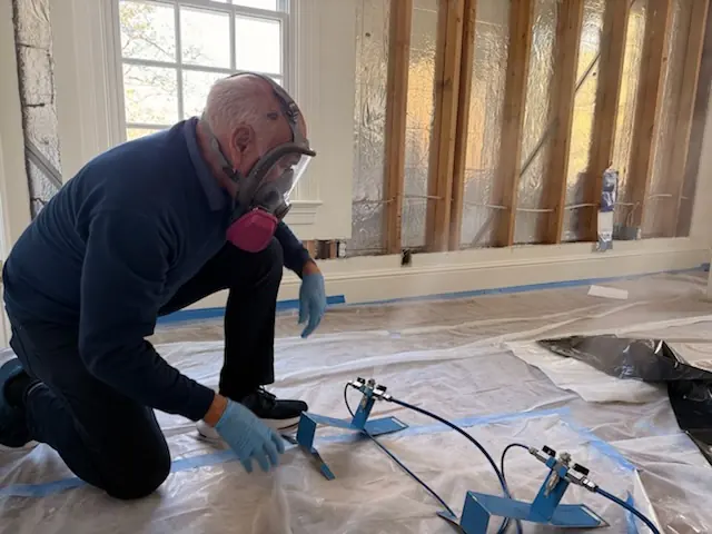 A restoration technician setting drying equipment in a Stamford home stripped to the studs